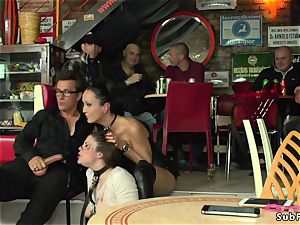 domme in leather dominates sub in public